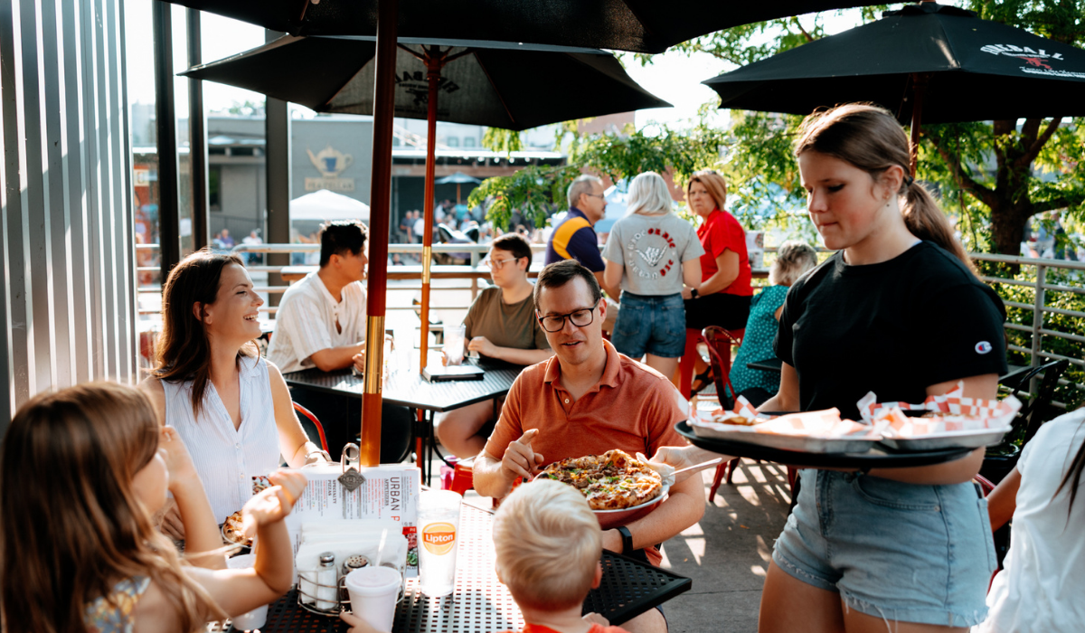 serving pizza to a family on an outdoor patio
