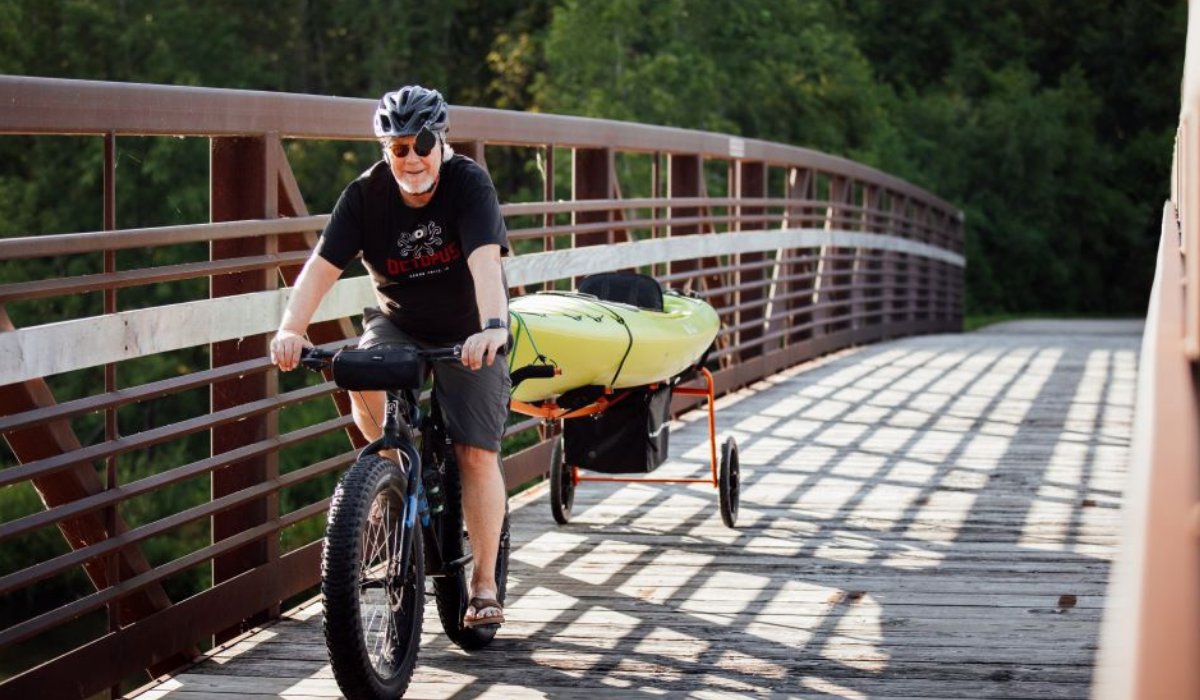 man on a bicycle pulling a kayak